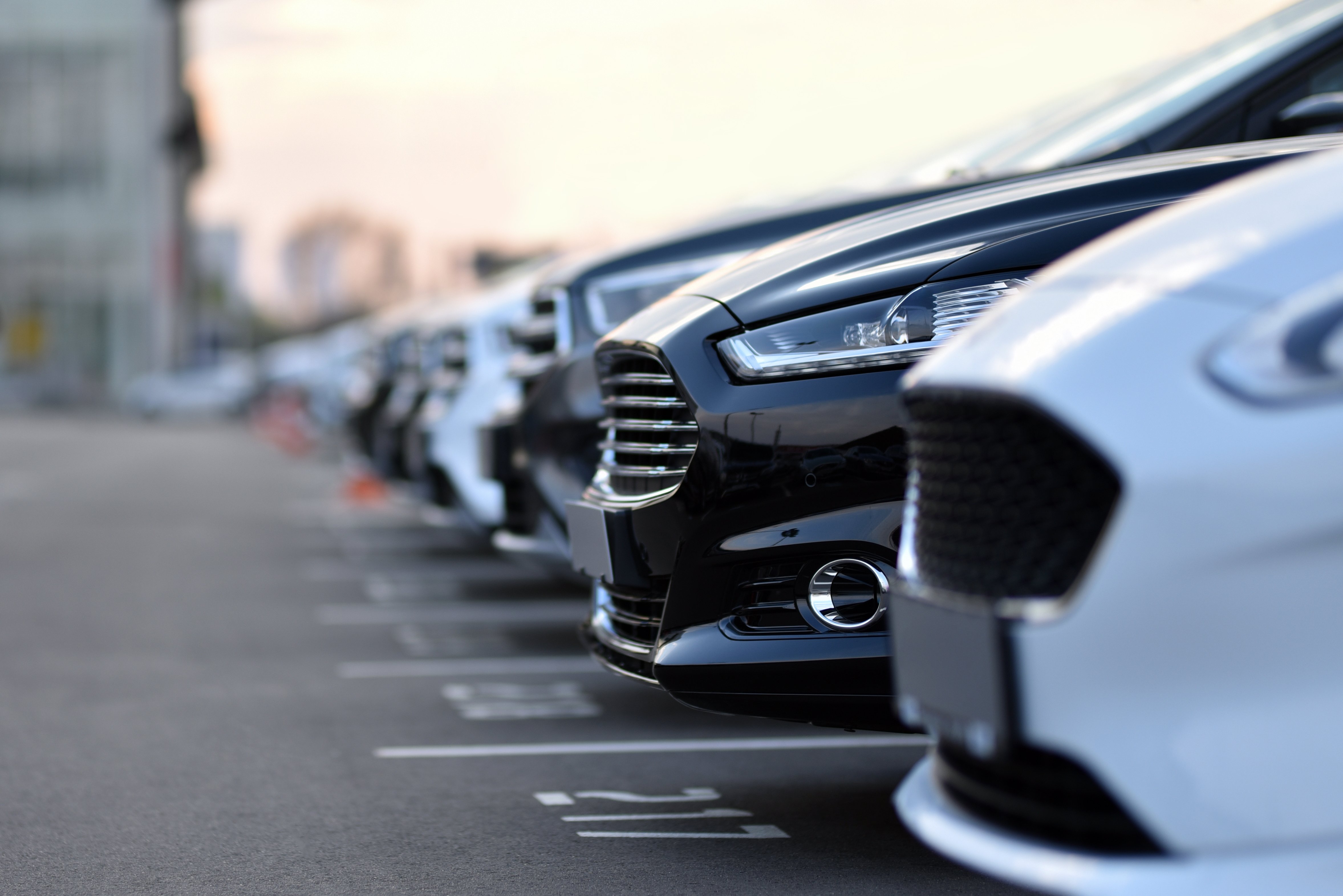 rows of black and white cars on a parking lot waiting to be sold