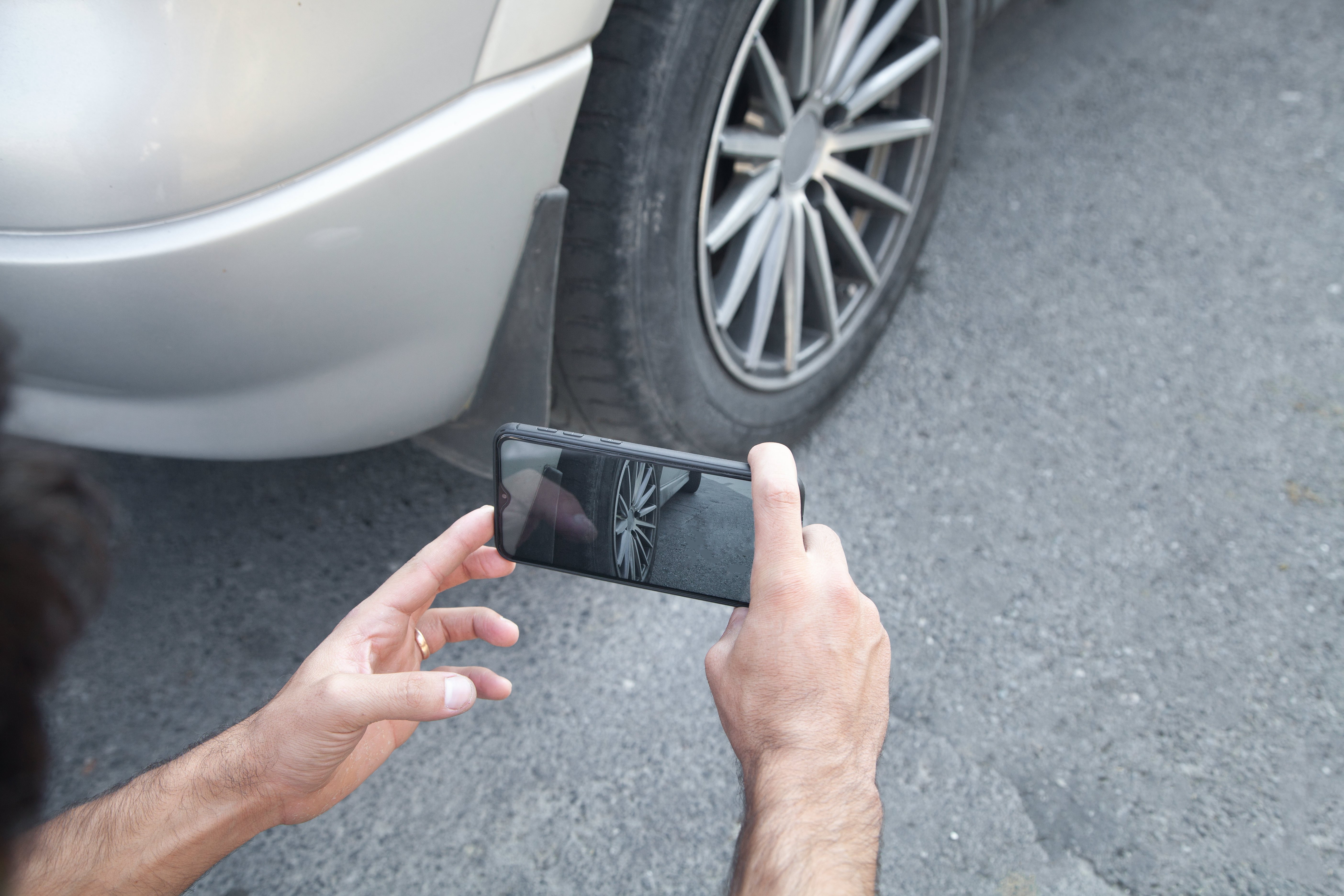 Person taking a photo of a car wheel on their phone